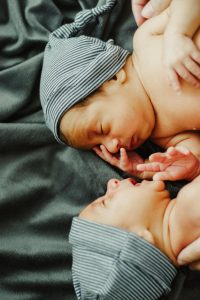 newborn twins facing each other with matching hats